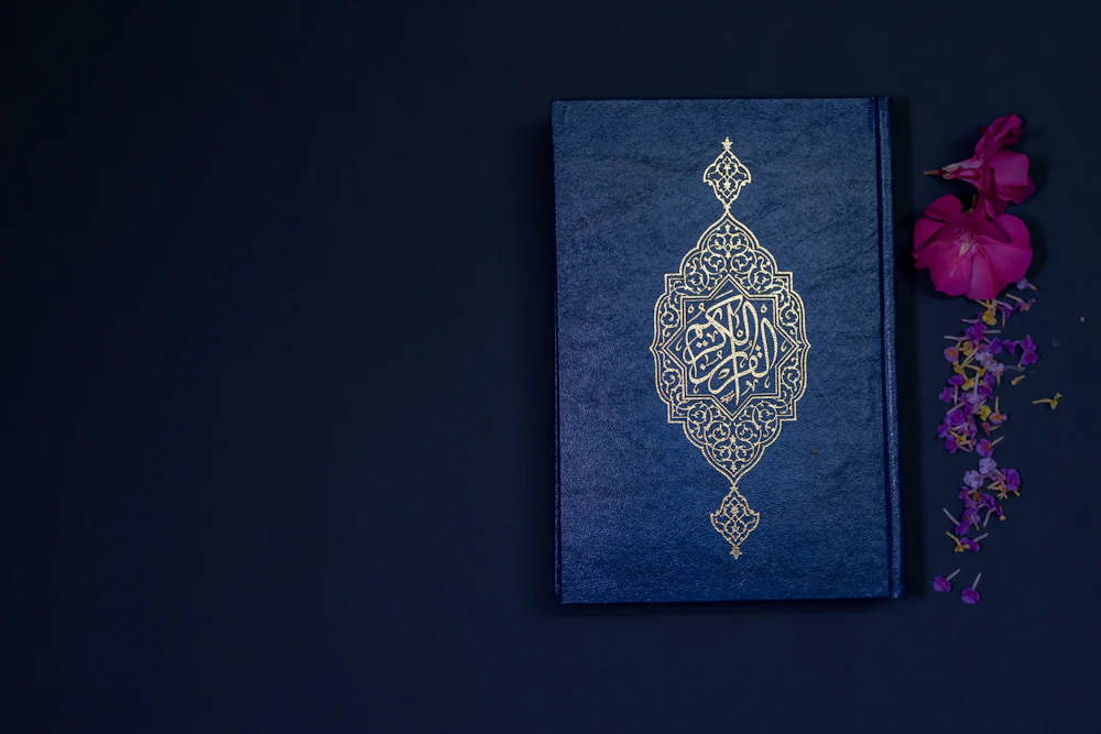 An open Quran resting beside a set of prayer beads